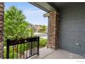 Inviting covered front porch with stone pillar, iron railing and view of the street at 15998 Humboldt Peak Dr, Broomfield, CO 80023