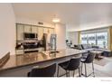 Open concept kitchen featuring stainless appliances, granite countertops, barstool seating, and an adjacent living area at 1623 Saint Paul St # 310, Denver, CO 80206