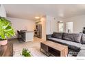 A modern living room featuring wood floors, a gray couch, black bar stools, and stainless appliances at 1623 Saint Paul St # 310, Denver, CO 80206