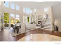 Sunlit living room with soaring ceilings, modern decor, fireplace, and adjacent dining area at 1644 Stardance Cir, Longmont, CO 80504