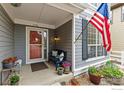 Inviting front porch with stylish decor, including potted plants, seating, and patriotic American flag at 1706 Naples Ln, Longmont, CO 80503