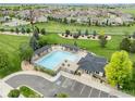 Aerial view of neighborhood pool, lounge chairs, mature trees, and community center at 1766 Montgomery Cir, Longmont, CO 80504