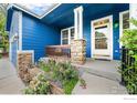 Inviting home entrance with stone pillars, a cozy porch, and colorful flower beds at 1874 Ute Creek Dr, Longmont, CO 80504