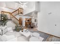 Inviting living room with vaulted ceilings, a wooden staircase, and an open layout to the kitchen at 2108 Meadow Ct, Longmont, CO 80501