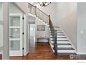 Bright foyer showcasing hardwood floors and an elegant staircase with iron railings at 2133 Indian Peaks Cir, Longmont, CO 80504