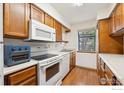 Functional kitchen featuring wooden cabinets, white appliances, and hardwood floors, offering a cozy cooking space at 2249 Emery St # B, Longmont, CO 80501