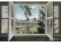 Scenic view of the tennis court and mountains through the window with white shutters at 4993 Clubhouse Ct, Boulder, CO 80301
