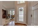 Inviting foyer featuring hardwood floors, a decorative glass door, and a view into the living room at 6255 Collegiate Dr, Highlands Ranch, CO 80130