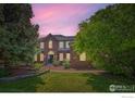 Charming brick home with a well-manicured lawn and mature landscaping, under a beautiful evening sky at 1005 Creek Ct, Longmont, CO 80503