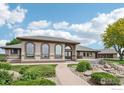 Attractive home exterior boasting arched windows, elegant landscaping, and a charming fountain at 10141 Yellowstone Rd, Longmont, CO 80504