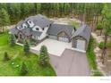 Aerial view of the home showing the three-car garage, additional one car garage, and treed lot at 10525 Wild Fox Pl, Franktown, CO 80116