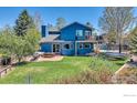 Aerial view of a large blue home with a patio, trampoline, and lush green lawn at 1067 W Alder St, Louisville, CO 80027