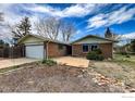 Traditional brick house with an attached garage and front yard with mature shrubs and garden area at 12891 Columbine Dr, Longmont, CO 80504