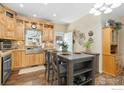 Eat-in kitchen with wood cabinets, stainless appliances, stylish backsplash, and an island with seating at 6125 Mallow Grn, Frederick, CO 80530