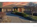 Exterior home view showing a 3-car garage, stone accents and a lush green lawn at dusk at 6260 Rain Dance Trl, Littleton, CO 80125