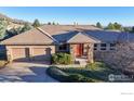 Ranch style home with three-car garage, stone accents and a well-maintained lawn and an orange front door at 6260 Rain Dance Trl, Littleton, CO 80125