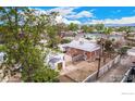 Aerial view of the brick home, detached garage, and fenced backyard in a neighborhood with mature trees at 8110 Ivy St, Commerce City, CO 80022