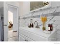 Bathroom featuring a white vanity with elegant tile walls and stylish fixtures at 8110 Ivy St, Commerce City, CO 80022