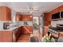 Modern kitchen featuring wood cabinets, stainless steel appliances, and hardwood floors with a ceiling fan at 8110 Ivy St, Commerce City, CO 80022
