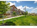 A row of modern townhomes with manicured lawns and a walking path on a sunny day at 1125 Anker Dr, Erie, CO 80516