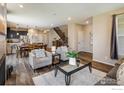 Open-concept living room with hardwood floors and stylish furnishings adjacent to kitchen and dining area at 1125 Anker Dr, Erie, CO 80516