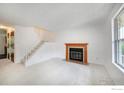 Bright living room with staircase, featuring a cozy fireplace with mantel and neutral carpet at 118 Pheasant Run, Louisville, CO 80027