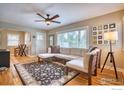 Bright living room featuring hardwood floors, a large window, and a modern ceiling fan at 1233 Carolina Ave, Longmont, CO 80501
