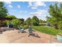 A backyard featuring a patio with comfortable seating, a lush lawn, mature trees, and a charming pergola at 1279 Greening Ave, Erie, CO 80516