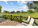 Peaceful view of yard overlooking a vast green space with a wooden fence, foliage, and clear blue skies at 1279 Greening Ave, Erie, CO 80516
