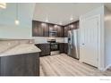Spacious kitchen features dark cabinetry, stainless steel appliances, granite countertops, and light hardwood floors at 2435 Calais Dr # G, Longmont, CO 80504