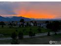 Stunning sunset view with vibrant colors over the mountains and neighborhood landscape at 3223 Castle Peak Ave, Superior, CO 80027