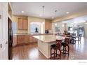 Modern kitchen with granite countertops, stainless steel appliances, a center island, and hardwood flooring throughout at 1060 Arrowhead Ct, Erie, CO 80516