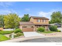 Two-story home showcasing a stone facade, complemented by a well-manicured lawn and a wooden garage door at 112 Melody Ln, Platteville, CO 80651