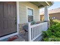 Inviting front porch with stone accents, white railing, seating and a welcoming front door at 1416 Monroe Ct, Longmont, CO 80501