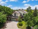 Aerial view of a two-story home with a three-car garage, mature trees, and well-maintained lawn at 1477 Akers Ct, Erie, CO 80516