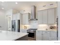 Well-lit kitchen featuring stainless steel appliances, white cabinets, and a stylish marble backsplash at 1631 Poplar Dr, Erie, CO 80516