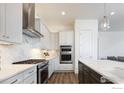 Modern kitchen with stainless steel appliances, white cabinetry, and marble backsplash for a sleek look at 1631 Poplar Dr, Erie, CO 80516
