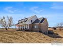 Charming two-story home with a welcoming front porch, set against a backdrop of a blue sky at 235 S County Road 23, Berthoud, CO 80513