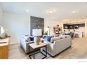 Bright living room featuring stylish sofas, modern fireplace, and an open layout to kitchen and dining area at 2738 Bear Springs Cir, Longmont, CO 80503