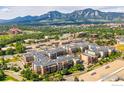 A high-angle shot showcases the buildings, landscaping, and mountain views of this Peloton community in Boulder, Colorado at 3301 Arapahoe Ave # 216, Boulder, CO 80303