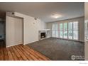 Living room with a fireplace, neutral carpet, and shuttered windows at 804 Summer Hawk Dr # 105, Longmont, CO 80504