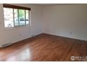 Bright living room offers hardwood floors, neutral walls and a large window overlooking the neighborhood at 829 Hubbard Dr, Longmont, CO 80504