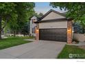 Charming two-story home showcasing a manicured lawn, brick accents, and a black garage door at 10216 Sandy Ridge Ct, Firestone, CO 80504