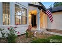 Inviting front porch with an American flag, lush garden bed, and charming architectural details at 10216 Sandy Ridge Ct, Firestone, CO 80504