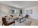 Cozy living room with hardwood floors, a plush sofa, stylish decor, and natural light from a large window at 12802 E Nevada Cir, Aurora, CO 80012