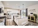 Bright kitchen featuring a center island, stainless steel appliances, granite countertops, and ample cabinet space at 12889 Clearview St, Firestone, CO 80504