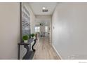 Bright hallway featuring elegant decor, light hardwood floors, and an open view into the dining area at 17871 E 96Th Pl, Commerce City, CO 80022
