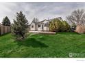 Expansive backyard with lush green grass, mature trees, and a welcoming patio area at 2132 Boise Ct, Longmont, CO 80504