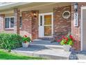 Inviting brick front porch with potted red geraniums, chair, and house number at 3124 Marlin Dr, Longmont, CO 80503