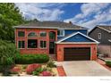 Inviting brick two-story home featuring a landscaped front yard filled with colorful flowers and mature trees at 3142 Captains Ln, Longmont, CO 80503